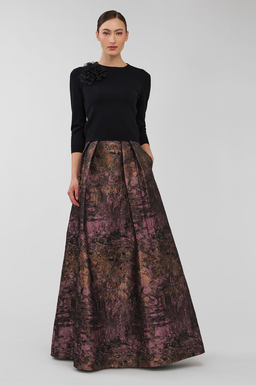 Woman wearing a black top and patterned skirt on a white background