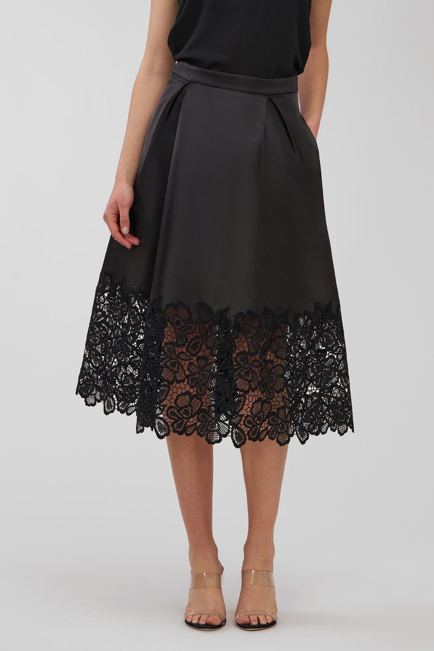 Black lace skirt worn by a person on a white background