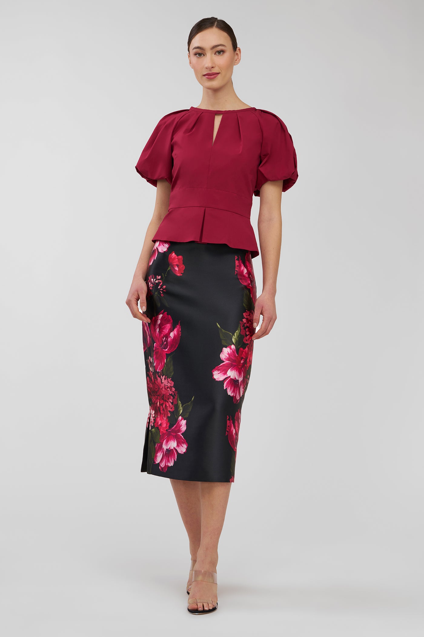 Woman wearing a red blouse and black floral skirt on a white background