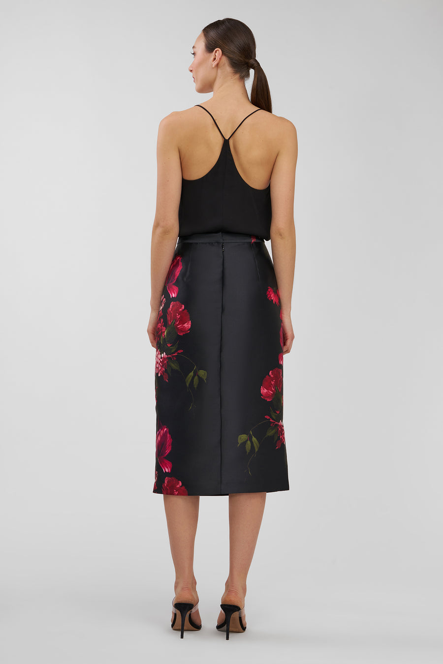 Woman wearing a black sleeveless top and floral skirt on a white background