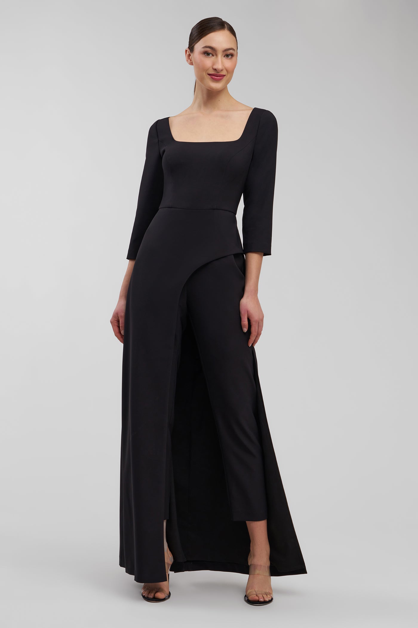 Woman wearing a black jumpsuit with a plain background