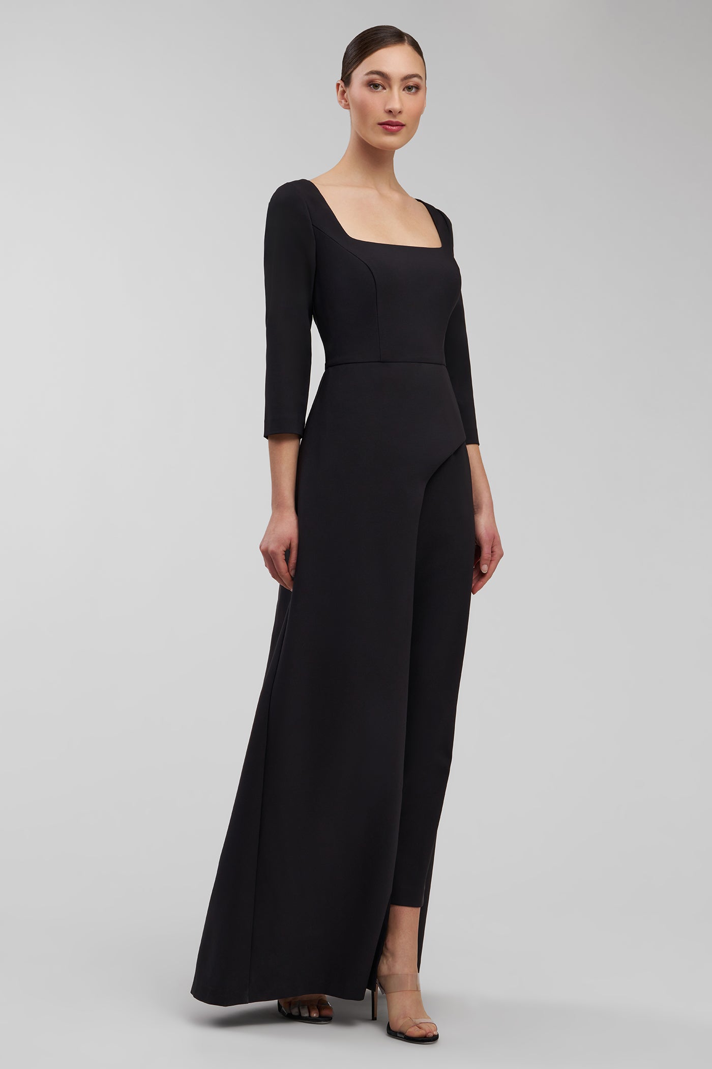 Woman wearing a black jumpsuit on a gray background