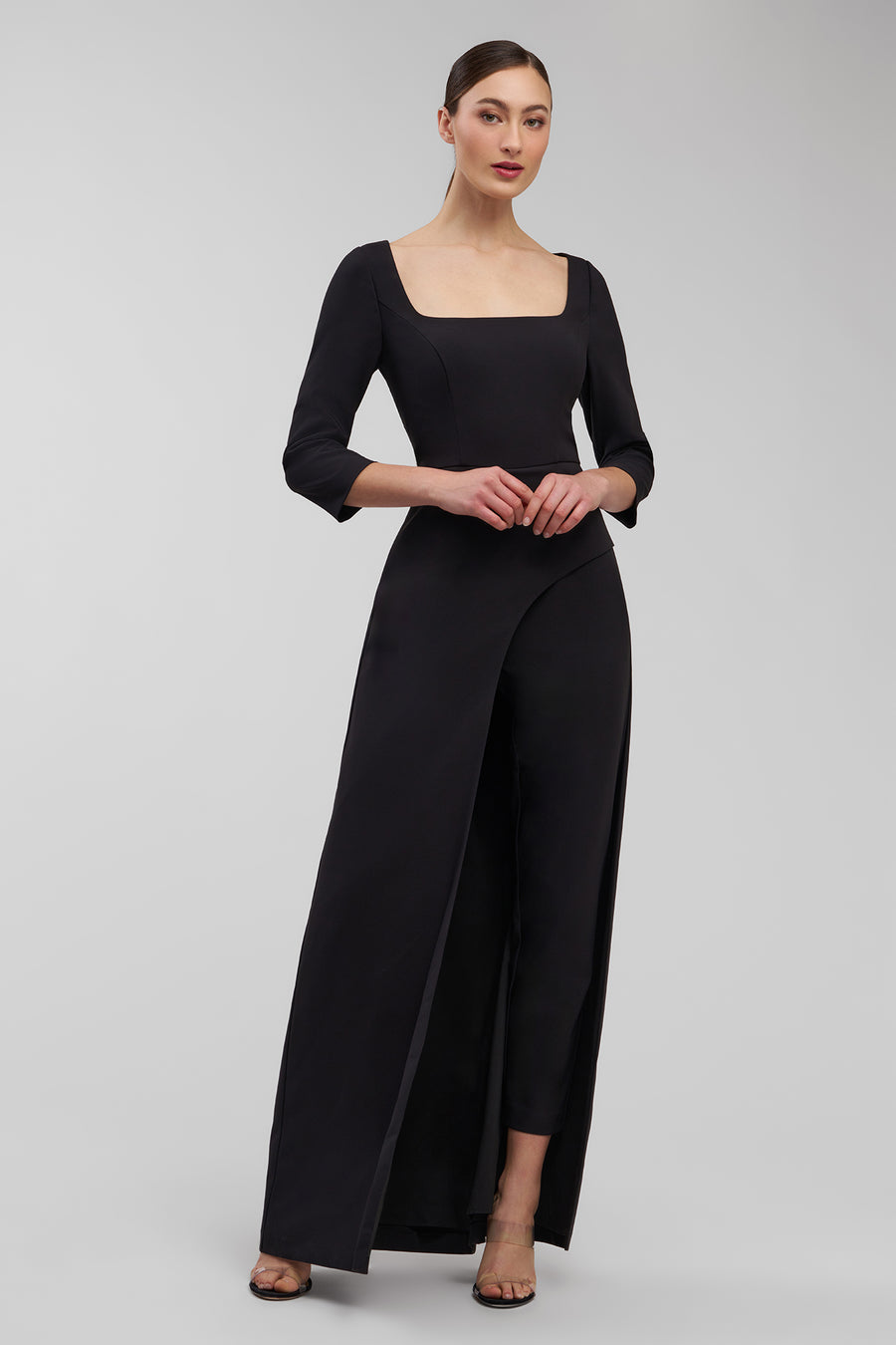 Woman wearing a black jumpsuit on a gray background