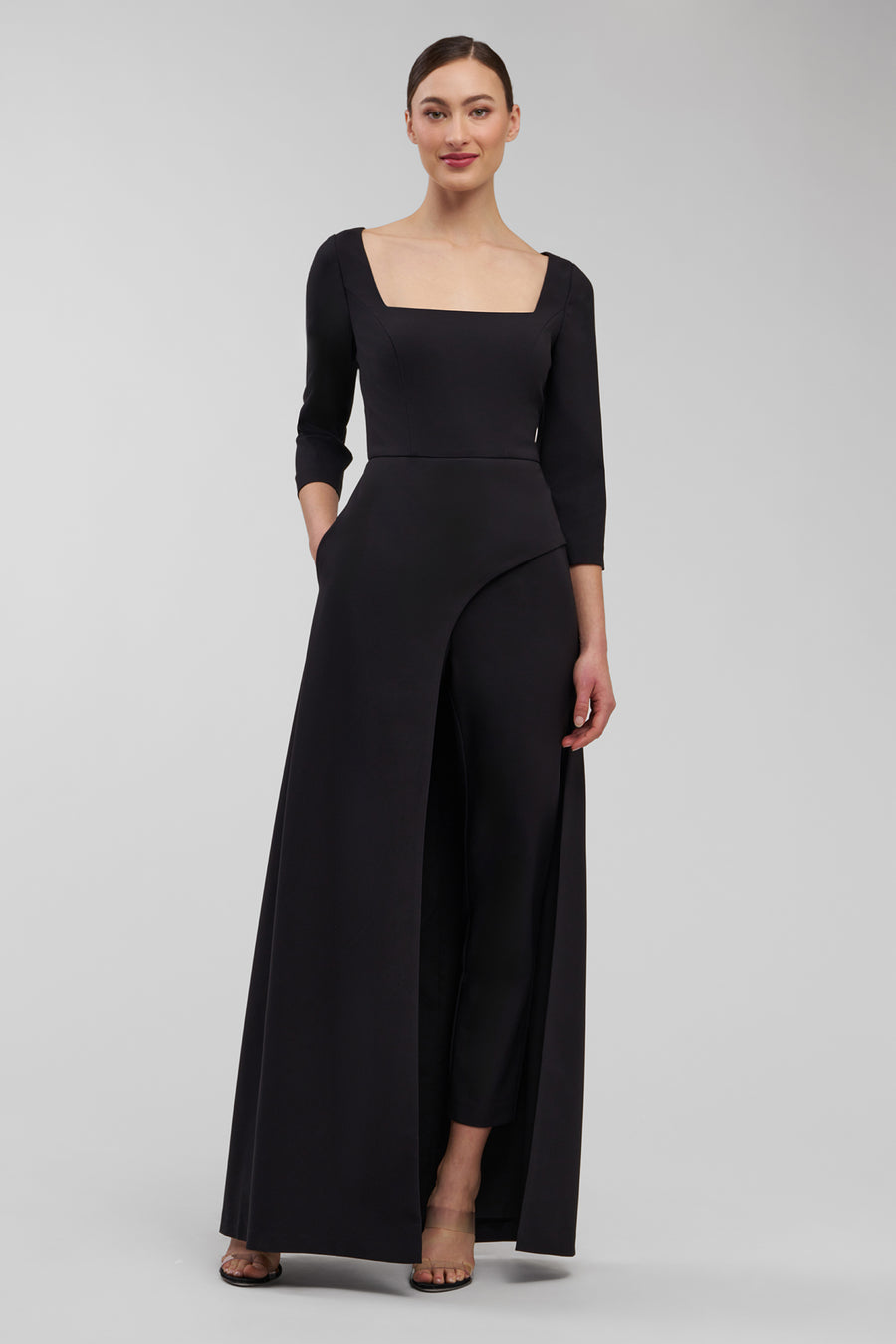 Woman wearing a black jumpsuit on a gray background