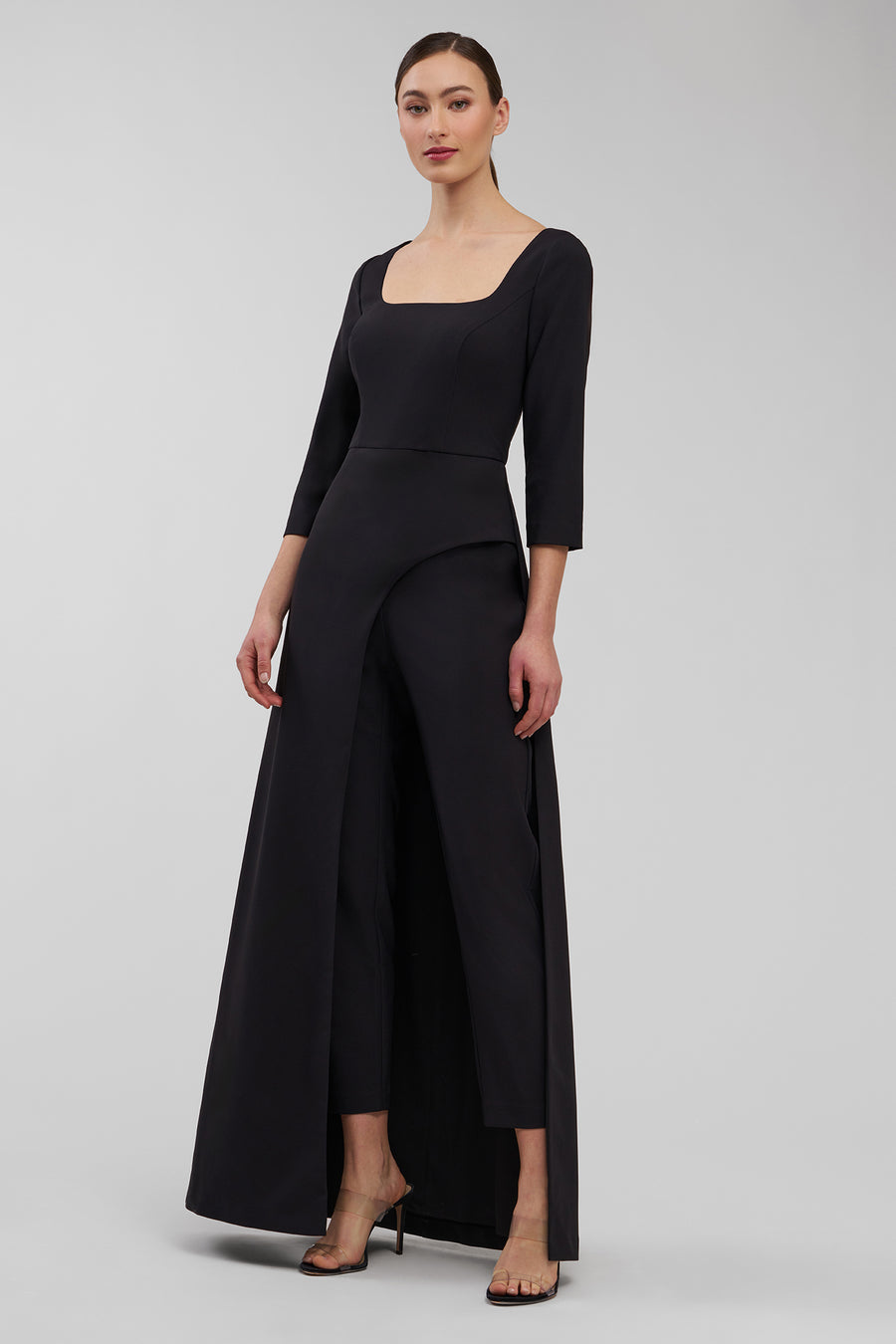 Woman wearing a black walk thru jumpsuit with a plain background
