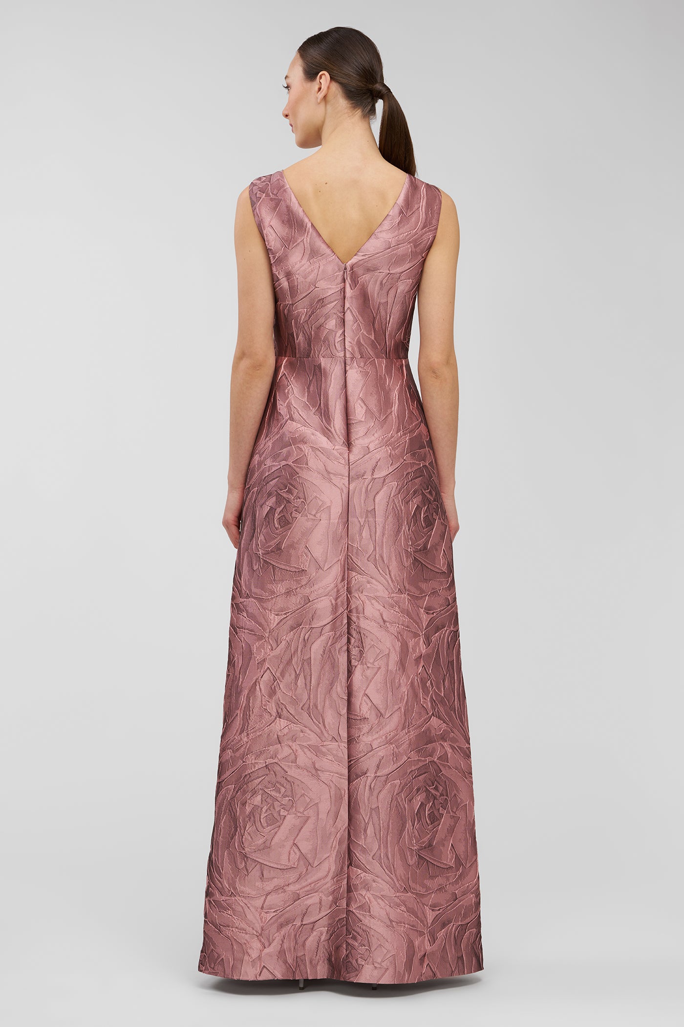 Woman wearing a pink patterned walk thru jumpsuit on a light gray background