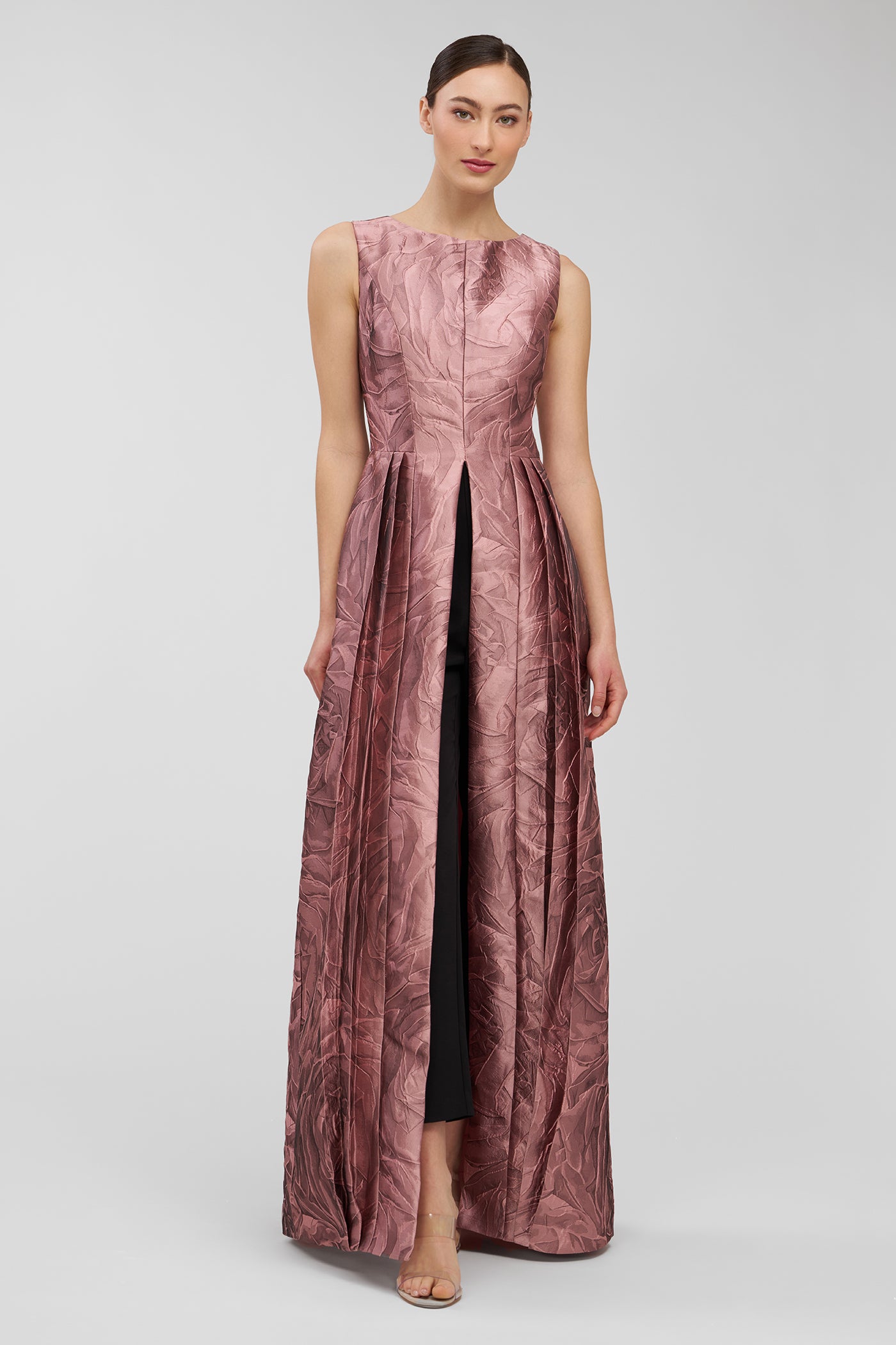 Woman wearing a long, patterned walk thru jumpsuit on a plain background