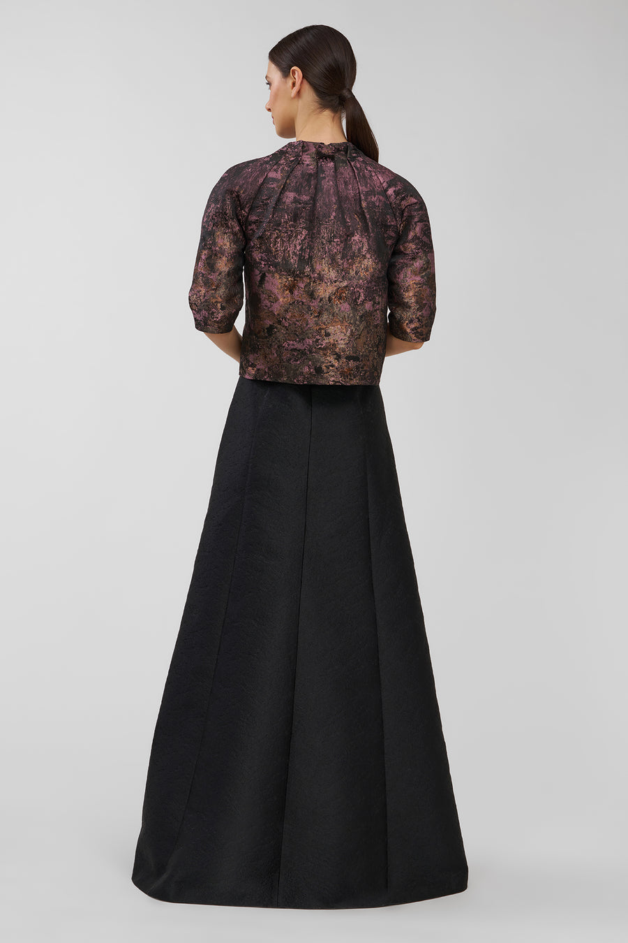 Woman wearing a patterned top and black skirt on a white background